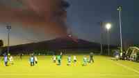 Noticia: Niños juegan al rugby sin prestar atención a la espectacular erupción de volcán Niños juegan al rugby sin prestar atención a la espectacular erupción de volcán